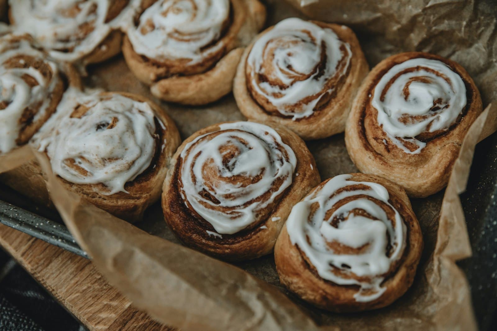 Kaneelbroodjes met wit glazuur op bakpapier, net uit de oven
