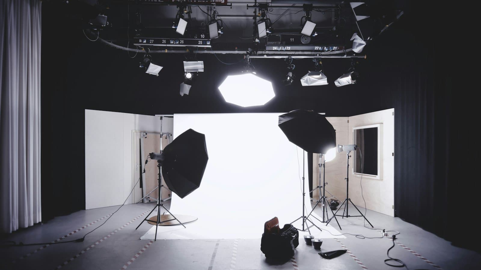 Lege fotostudio met een witte achtergrond, twee grote softboxen op statieven en lampen aan het plafond